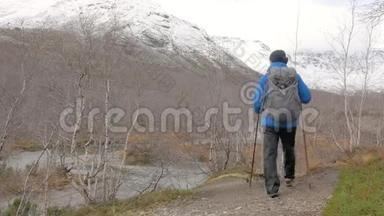 一个中年男人带着背包旅行一条山路。 他停下来，看着山顶，继续<strong>往前走</strong>。